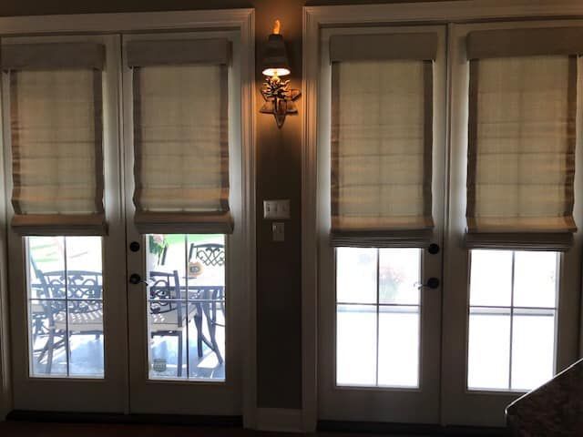 A living room with sliding glass doors and roman shades.