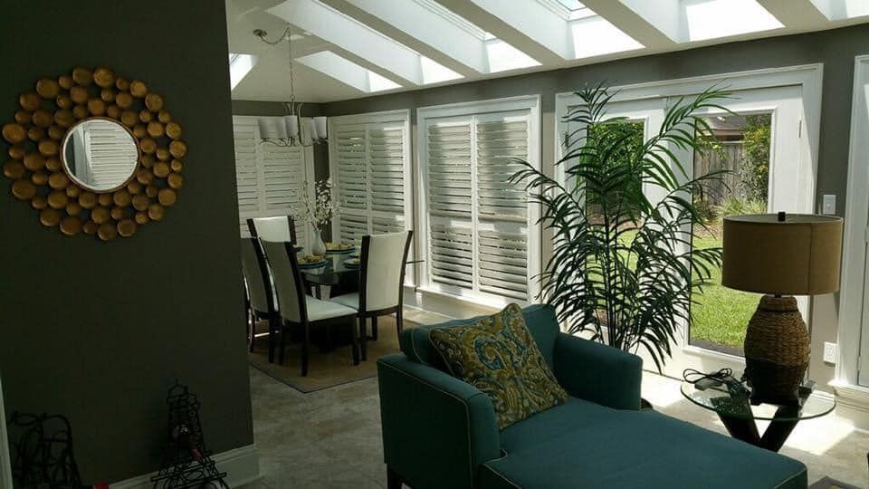 A living room with a couch , chair , lamp and mirror.