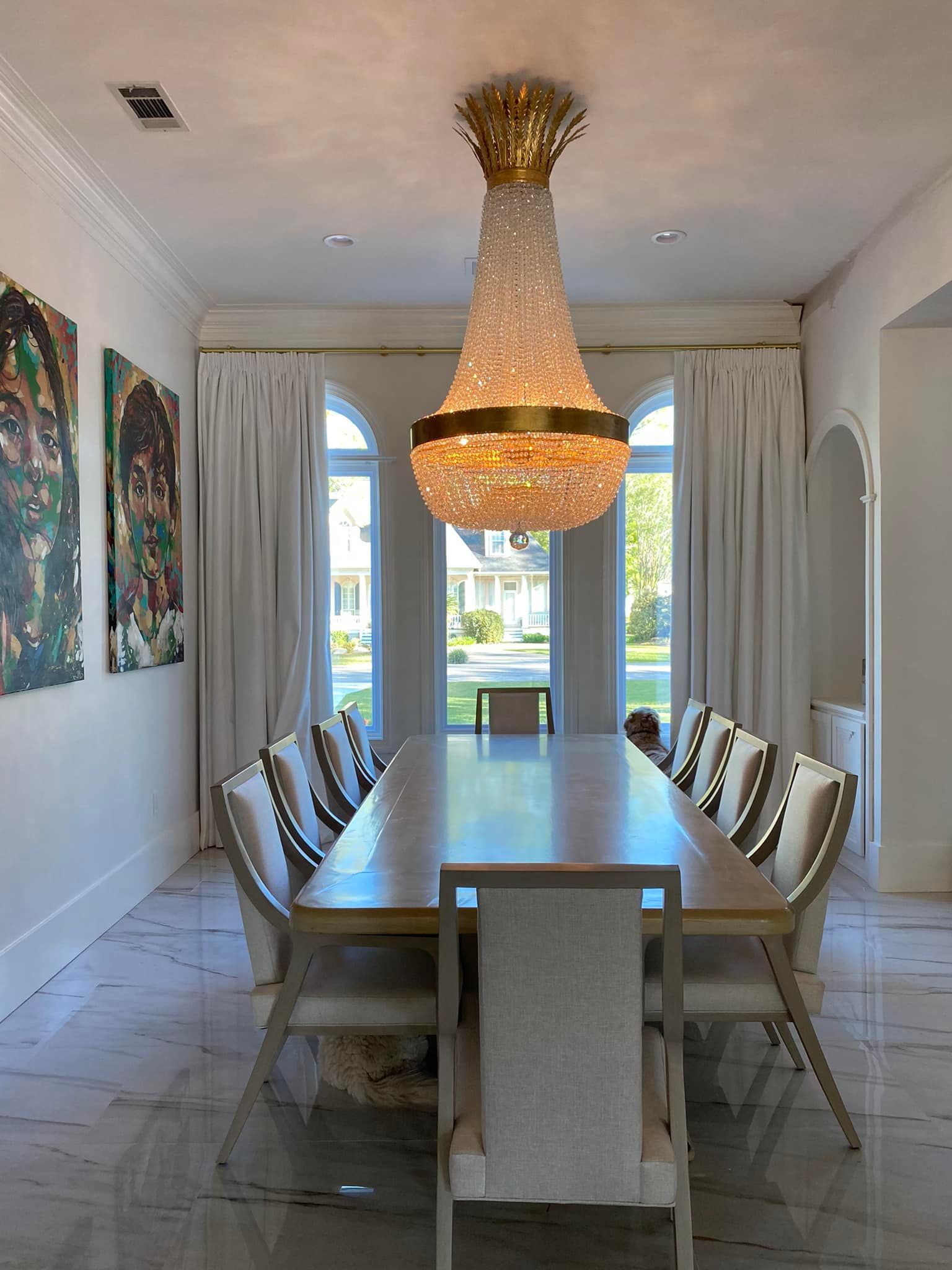 A dining room with a long table and chairs and a chandelier hanging from the ceiling.