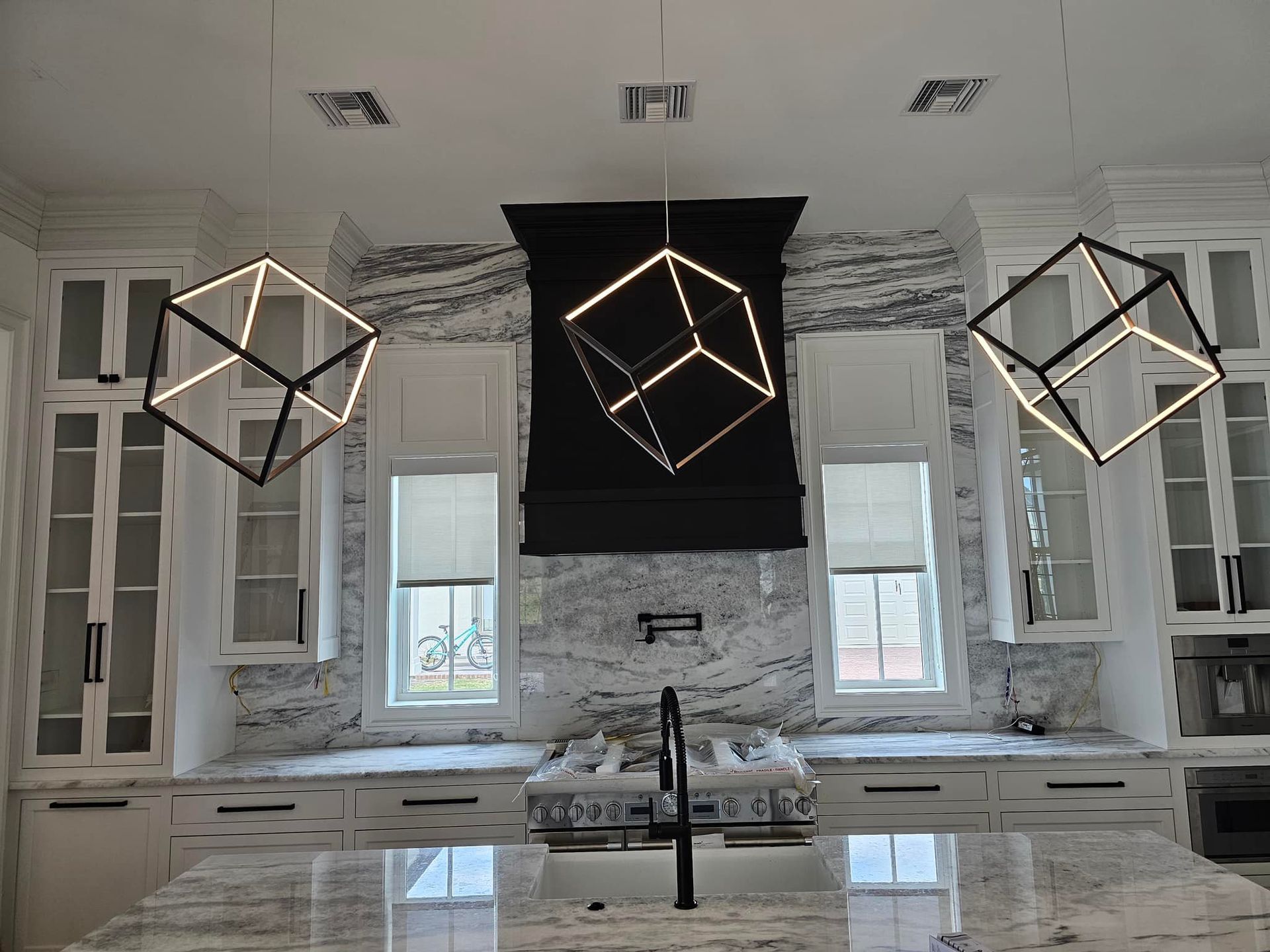 A kitchen with white cabinets , granite counter tops , a stove and a sink.