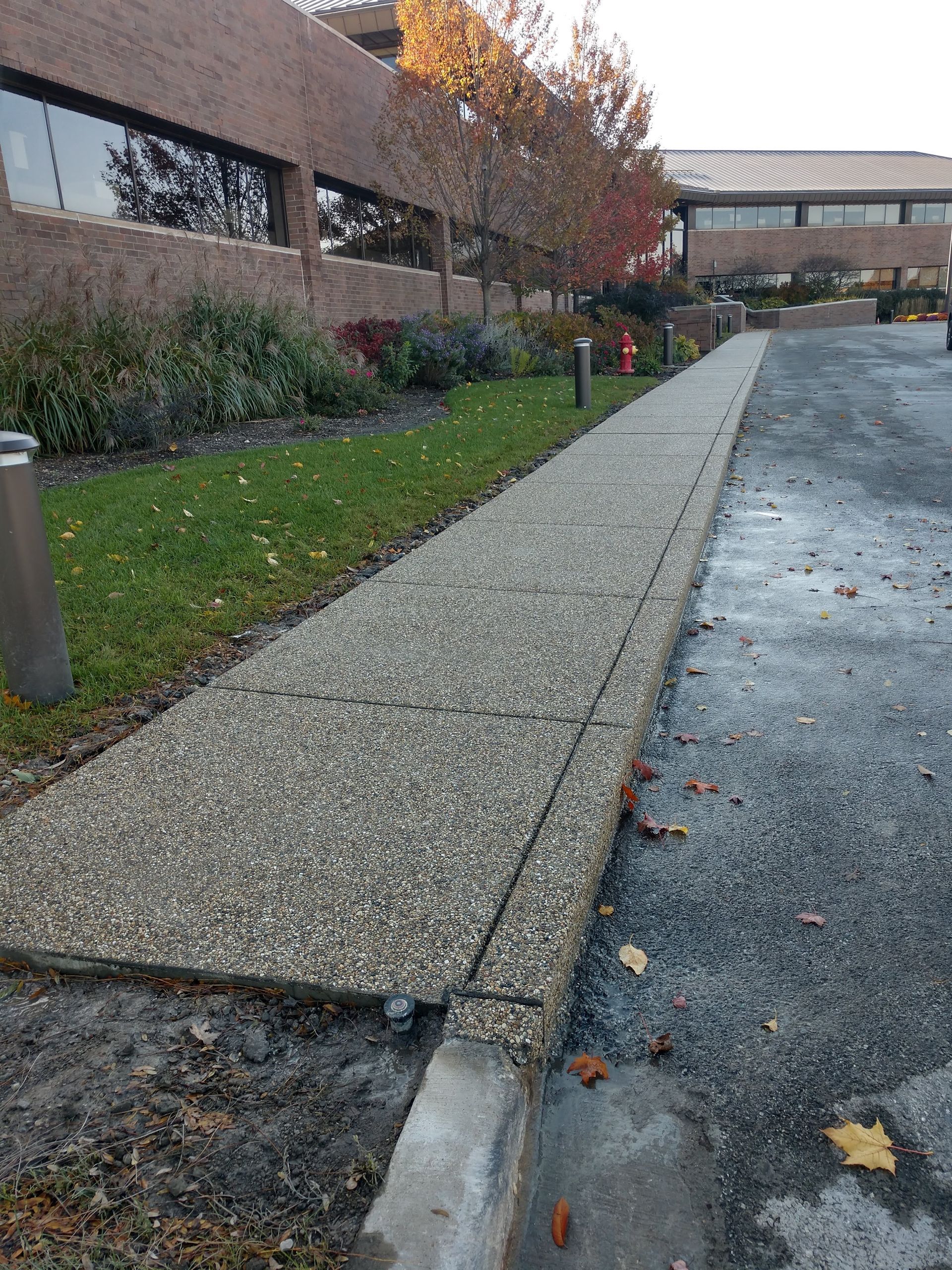 A sidewalk leading to a building with a brick building in the background.