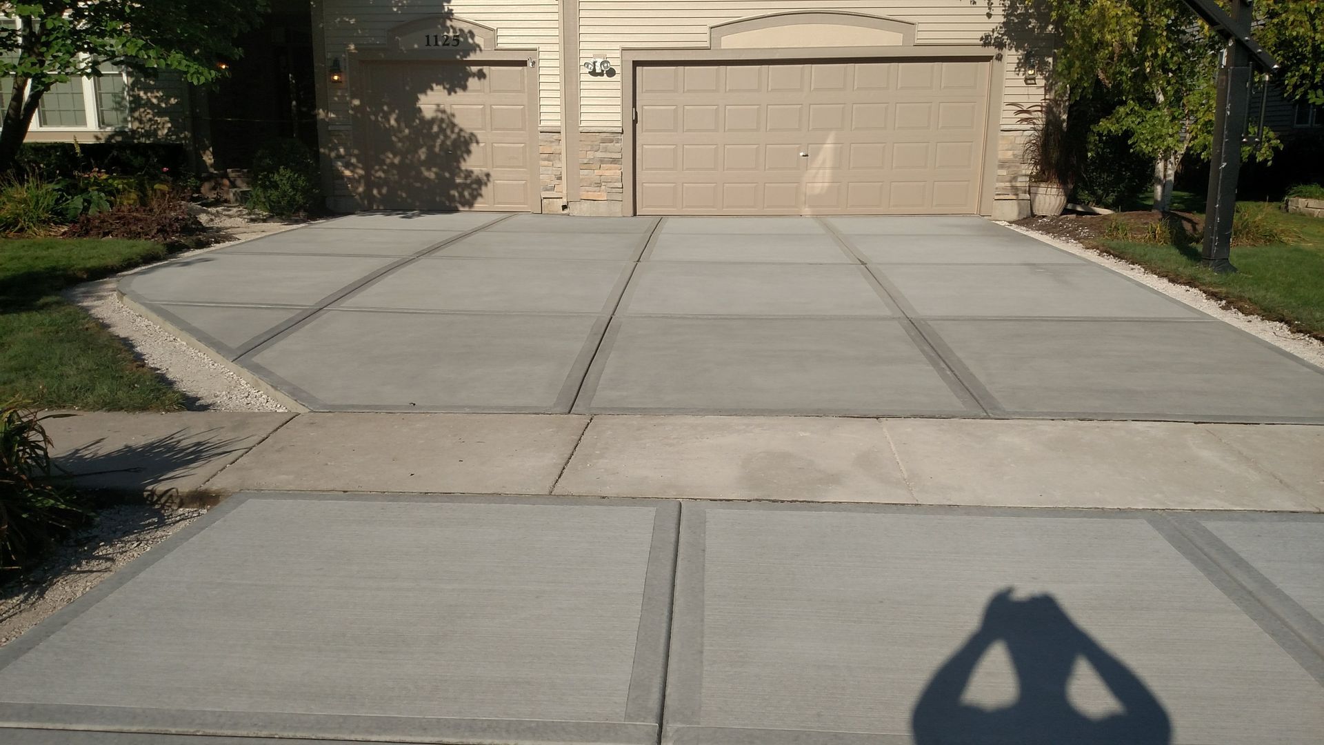 A shadow of a person taking a picture of a driveway