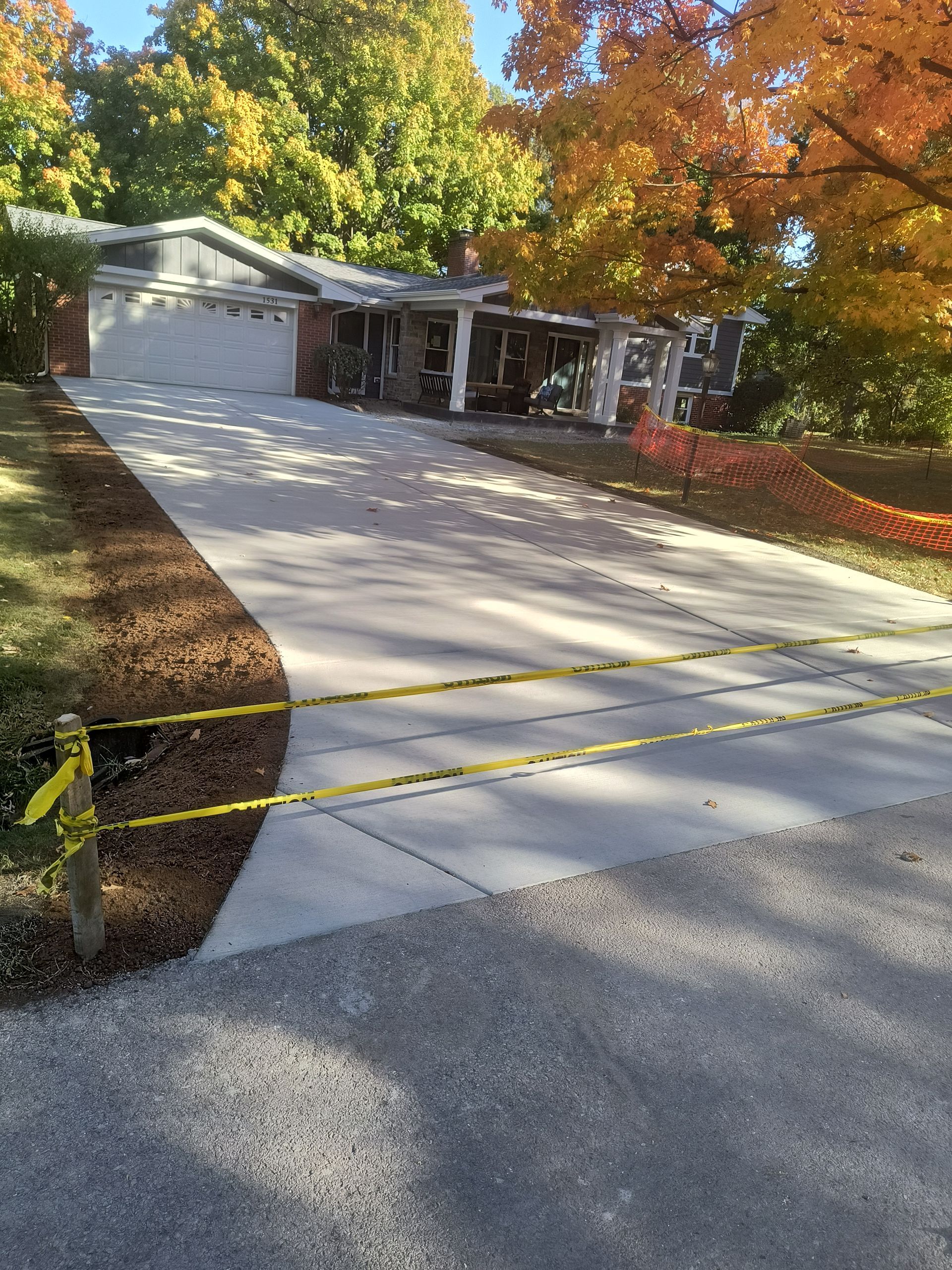 A concrete driveway leading to a house with trees in the background