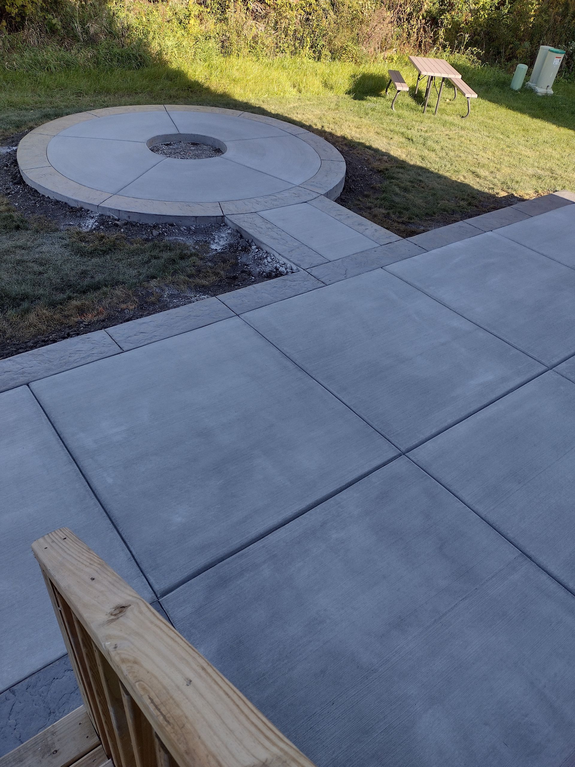 A concrete patio with a fire pit in the middle of it.