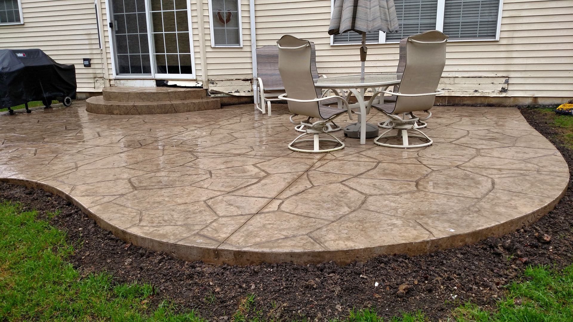 A patio with a table and chairs in front of a house.