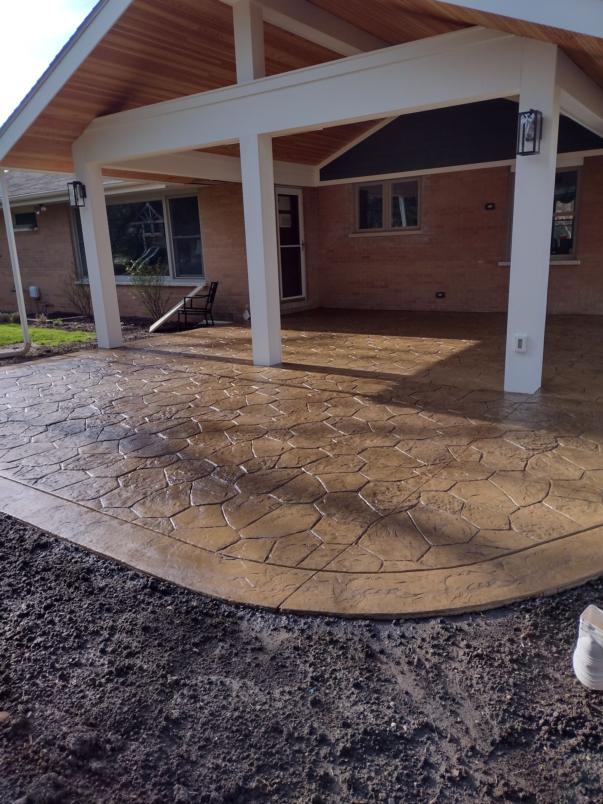 A brick house with a covered patio in front of it.