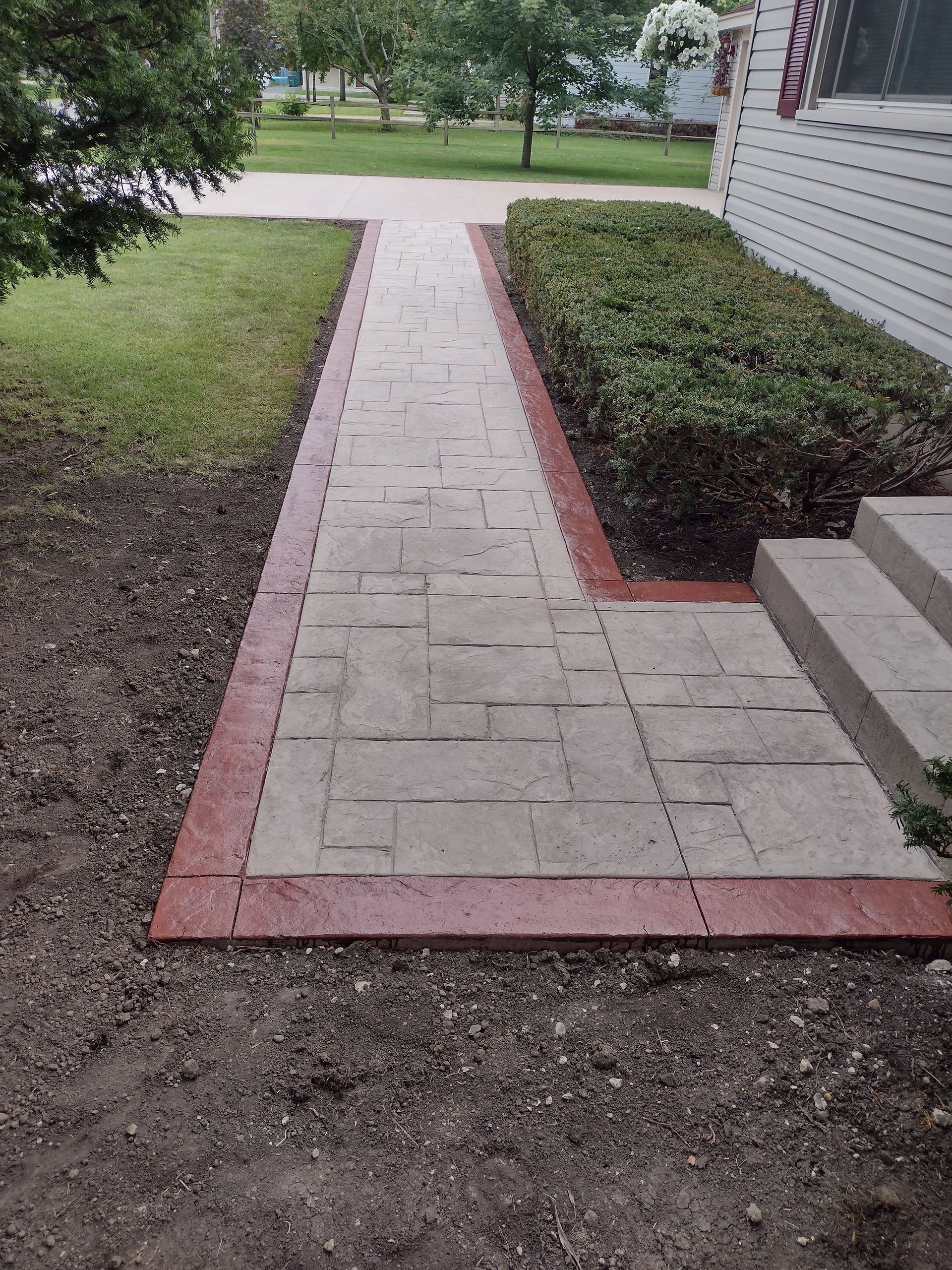 A brick walkway leading to a house with a red border.