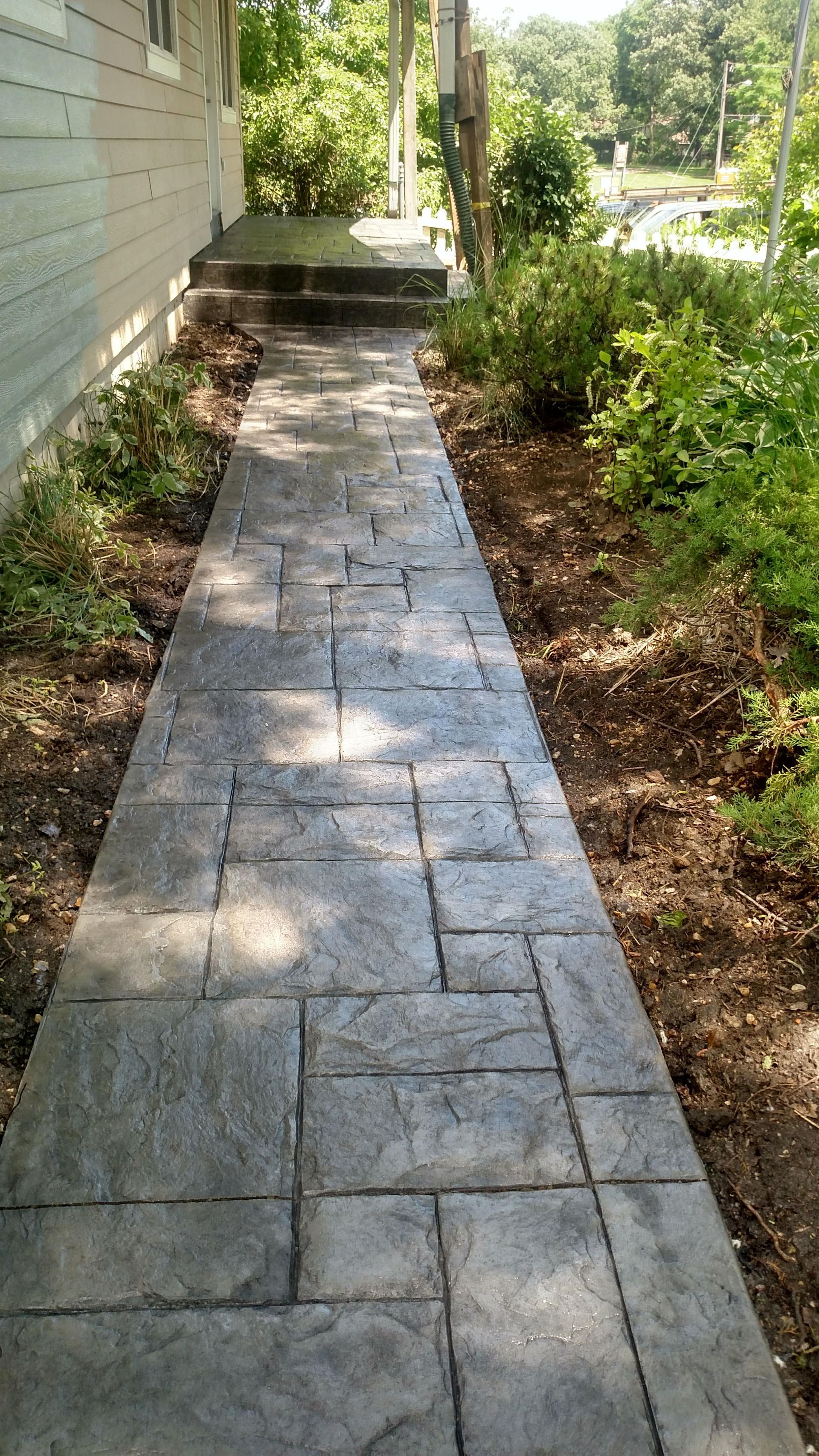 A concrete walkway leading to the side of a house.