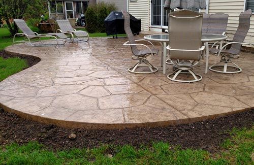 A patio with a table and chairs in front of a house.