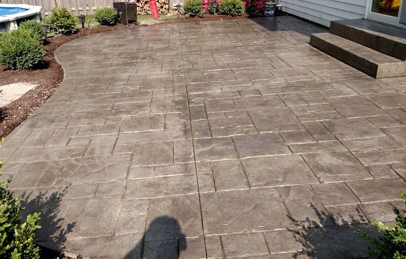 A patio with steps and a pool in the background.