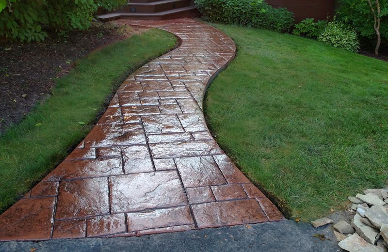 A brick walkway going through a lush green yard.