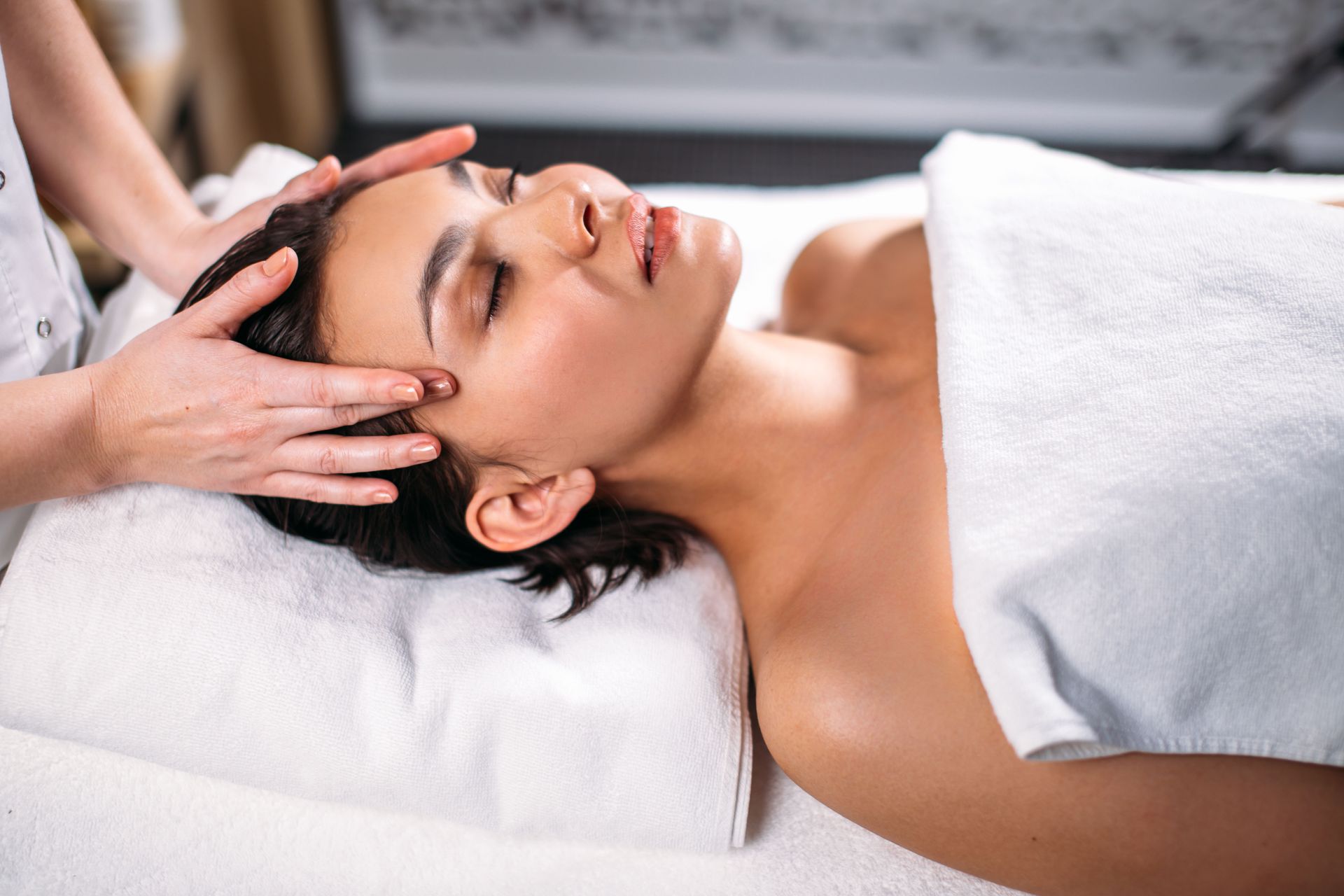 Spa therapist giving a facial massage to a relaxing client on a treatment table