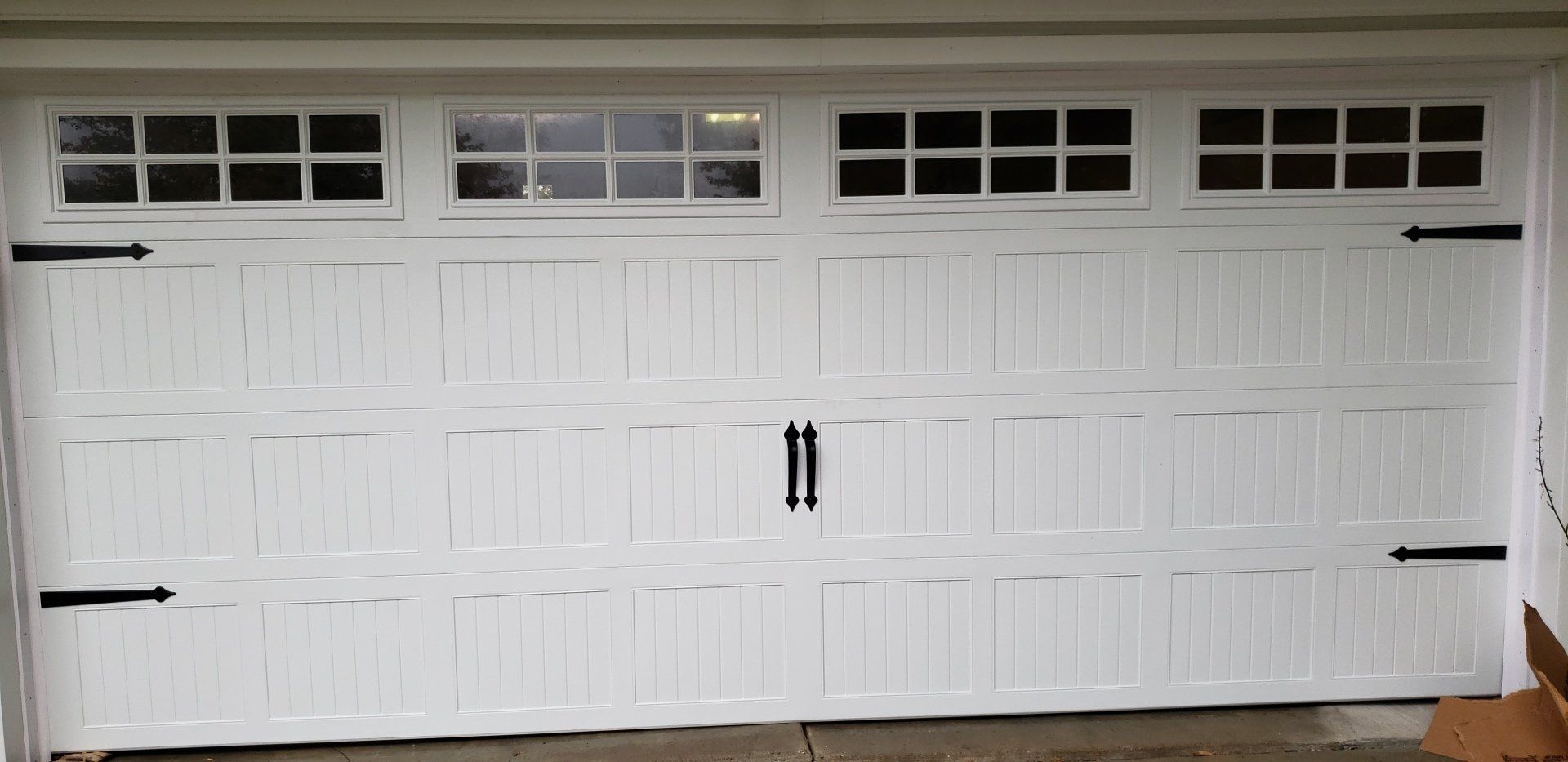 A white garage door with black handles and windows.