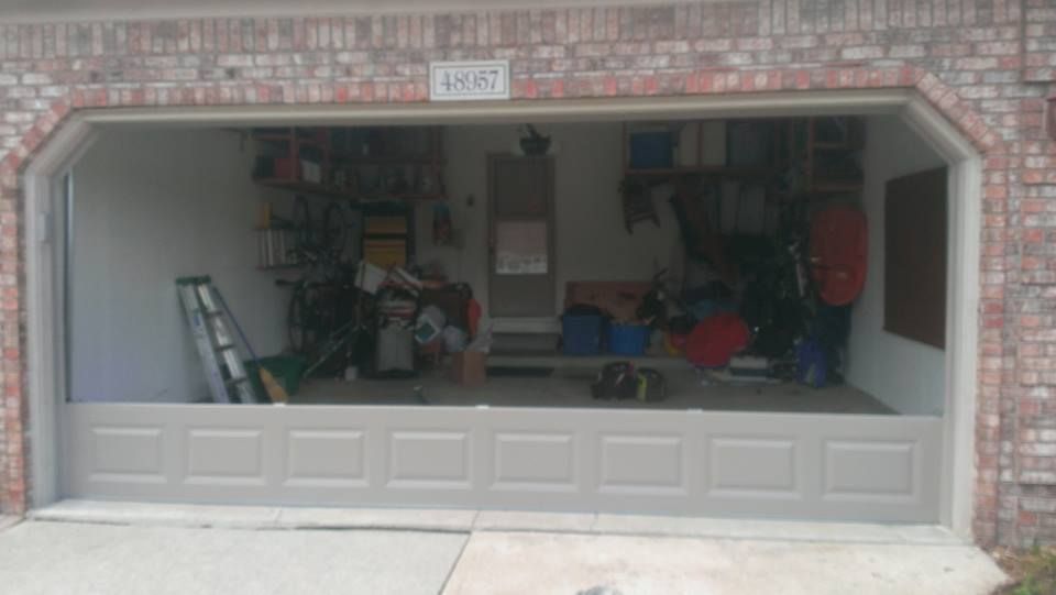 A garage door is open and filled with lots of items.