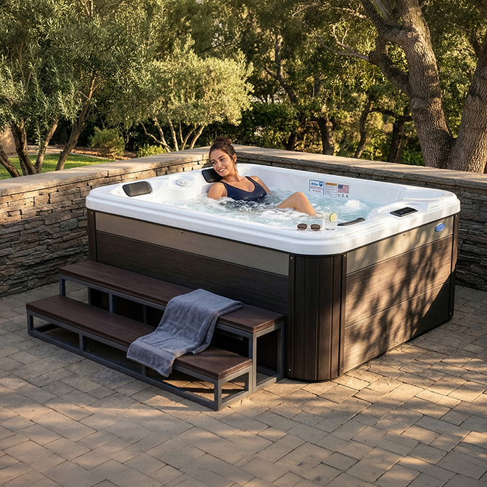 Person relaxing in a hot tub outdoors on a stone patio with trees in the background