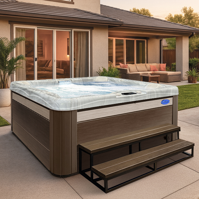 Backyard hot tub with brown siding and black steps on a patio outside a modern home