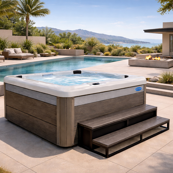 Luxury hot tub beside a modern pool on a sunny patio with mountain views