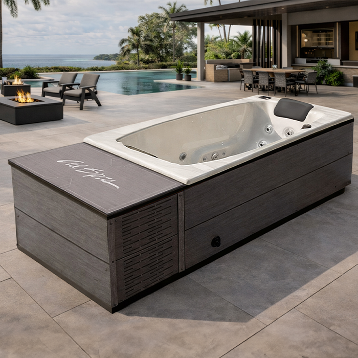 Modern outdoor hot tub beside an infinity pool on a patio overlooking the water