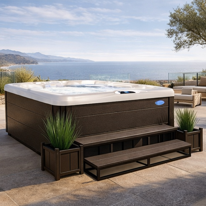Outdoor hot tub on a patio overlooking a calm coastal bay and distant hills