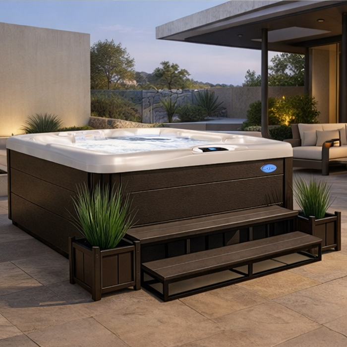 Modern rooftop patio with a large square hot tub, steps, and potted plants at dusk