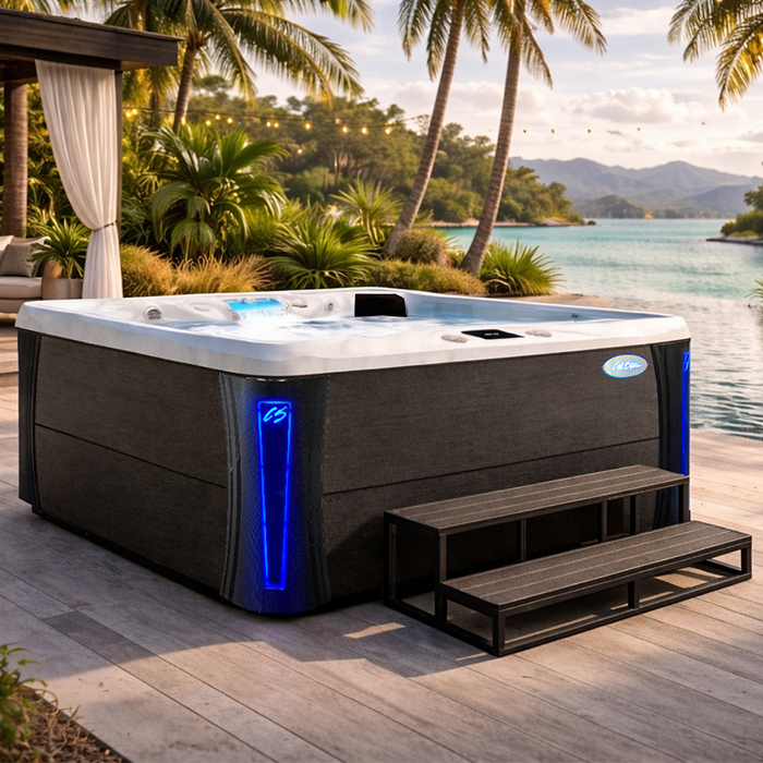 Modern hot tub with blue lights on a patio beside palm trees and a tropical beach at sunset