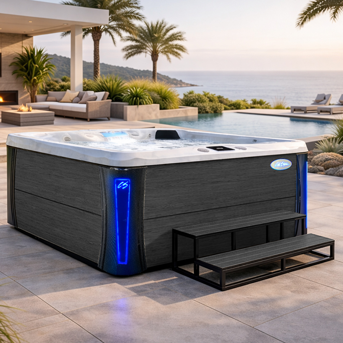 Modern gray hot tub with blue lights on a patio overlooking the ocean at sunset