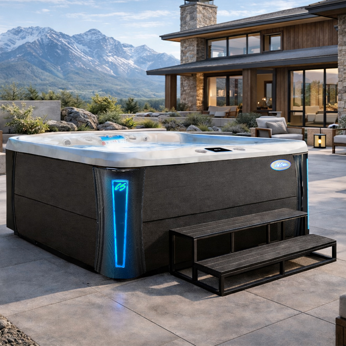 Lit hot tub on a modern patio with mountain view, beside a sleek house at dusk