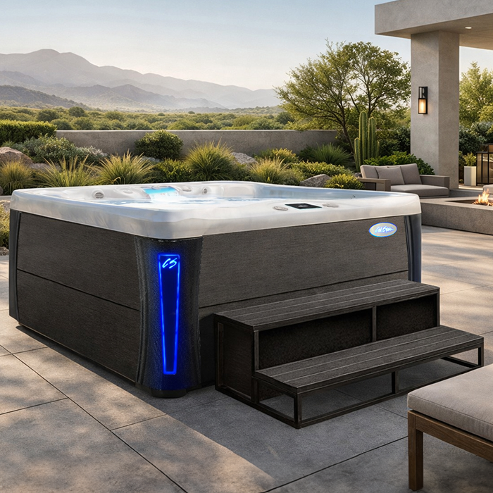 Modern backyard hot tub with blue accent light, steps, and mountain view at sunset