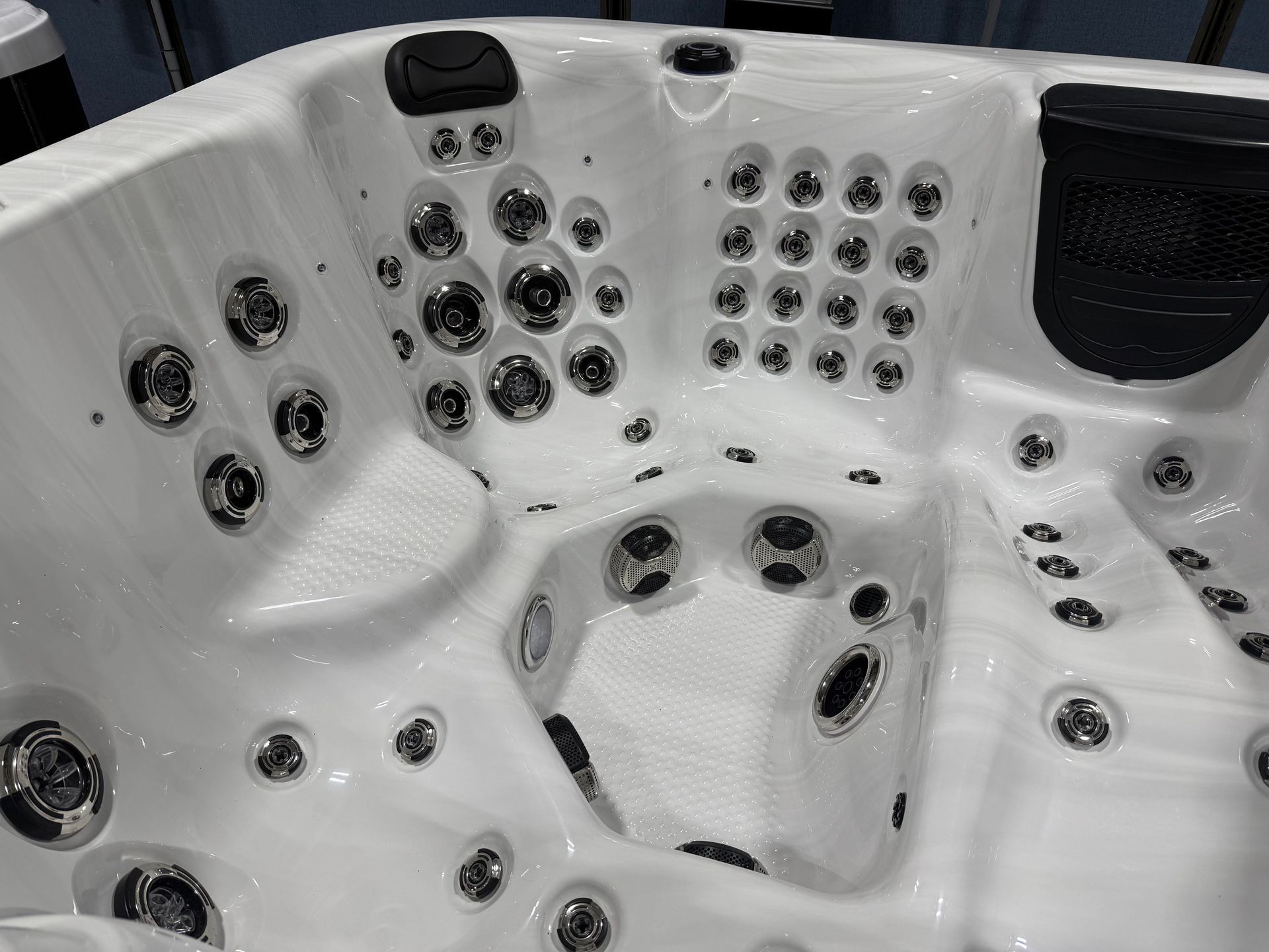 White hot tub interior with multiple jets and black headrests.