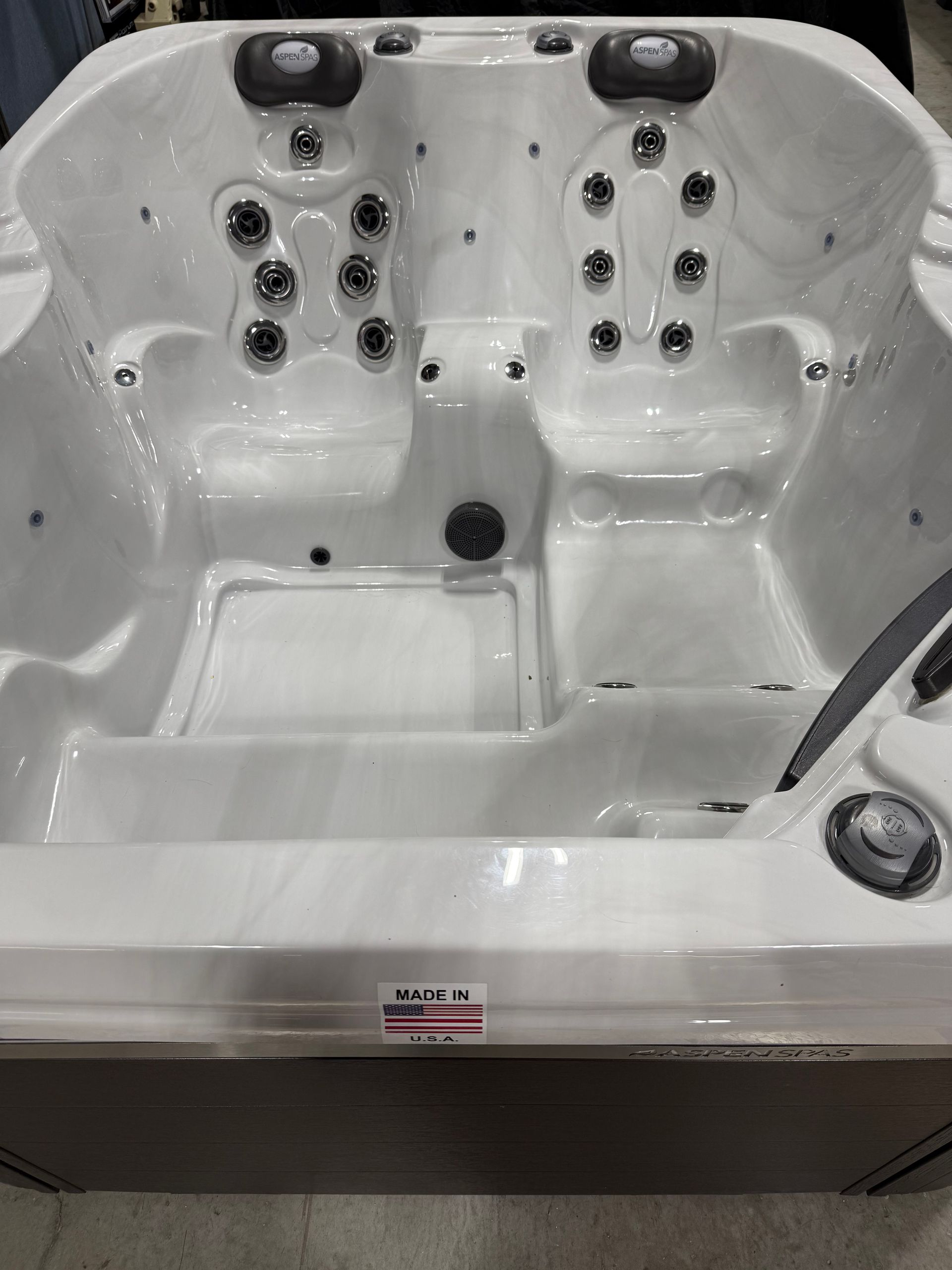 White hot tub interior with multiple jet nozzles and seating areas.