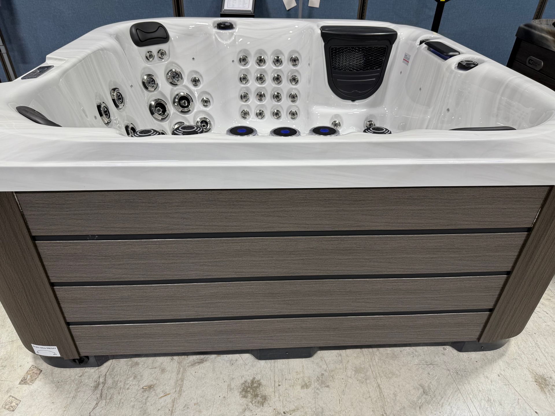 Hot tub with gray siding and white interior, jets and controls visible.