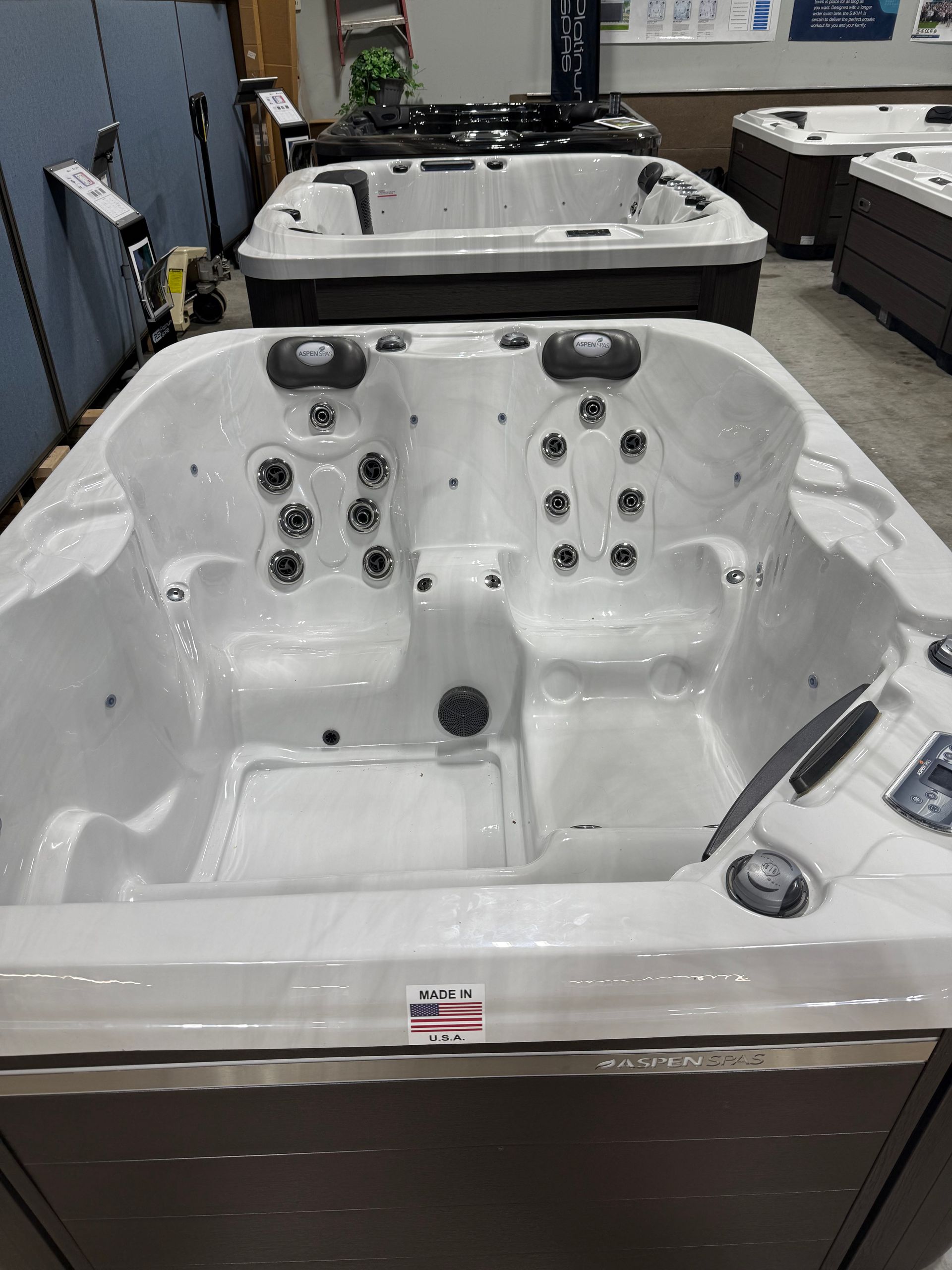 White hot tub with multiple jets on display in a store, with several other hot tubs visible.