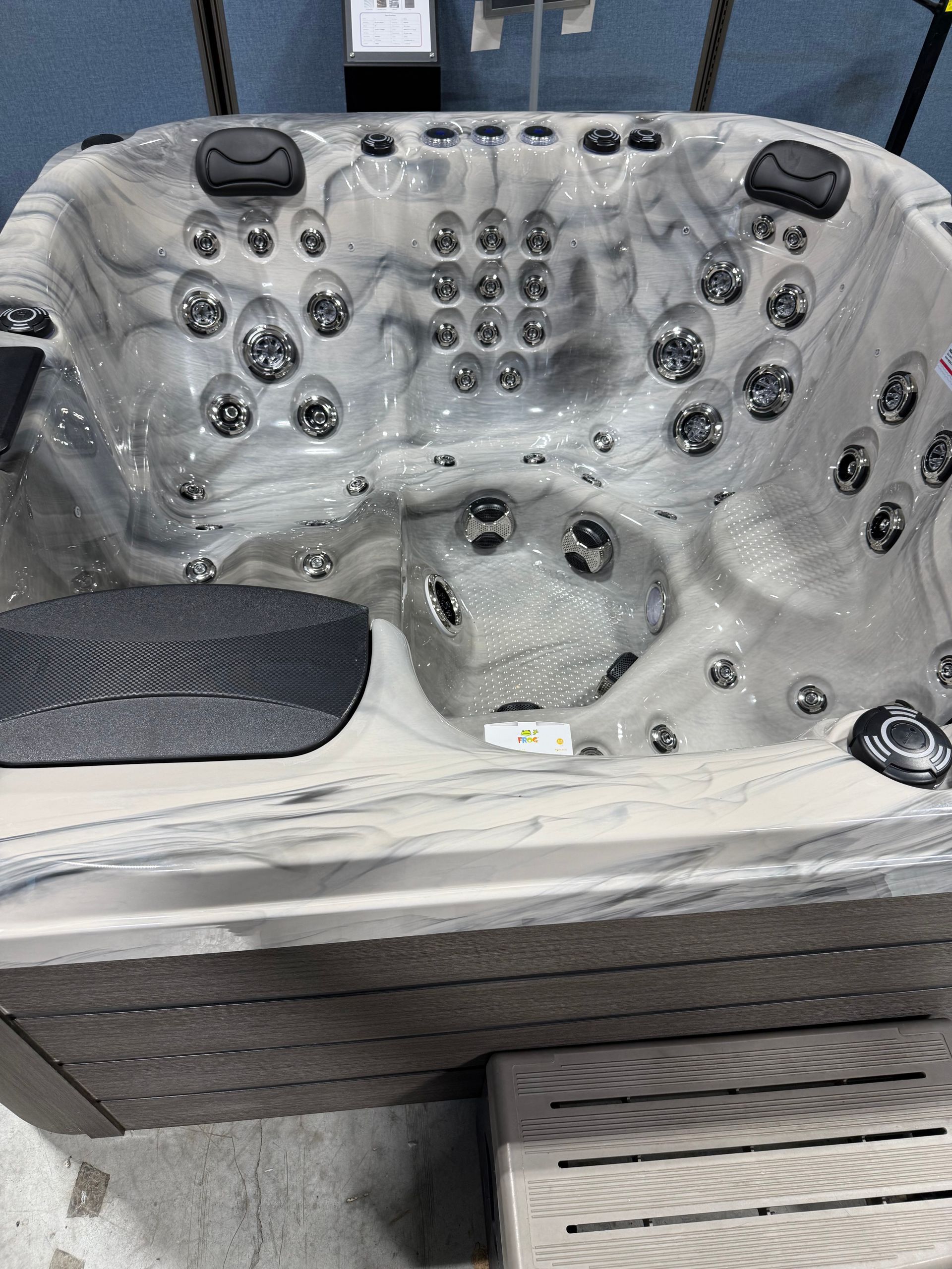 A grey and white marbled hot tub with numerous jets and a dark grey exterior.