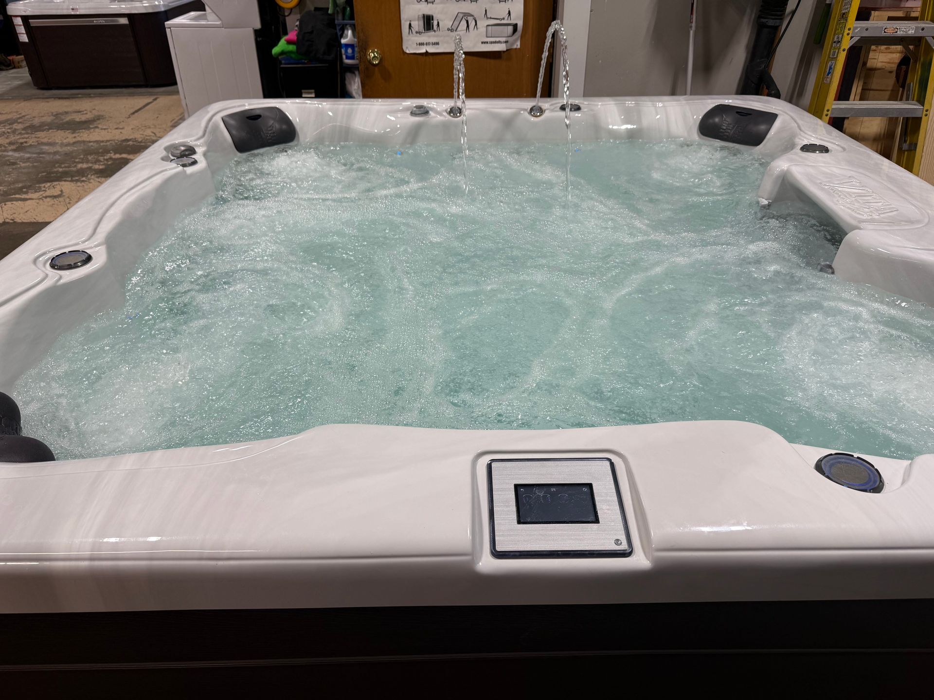 Hot tub with bubbling water, control panel, and dark surround. White trim and black headrests.