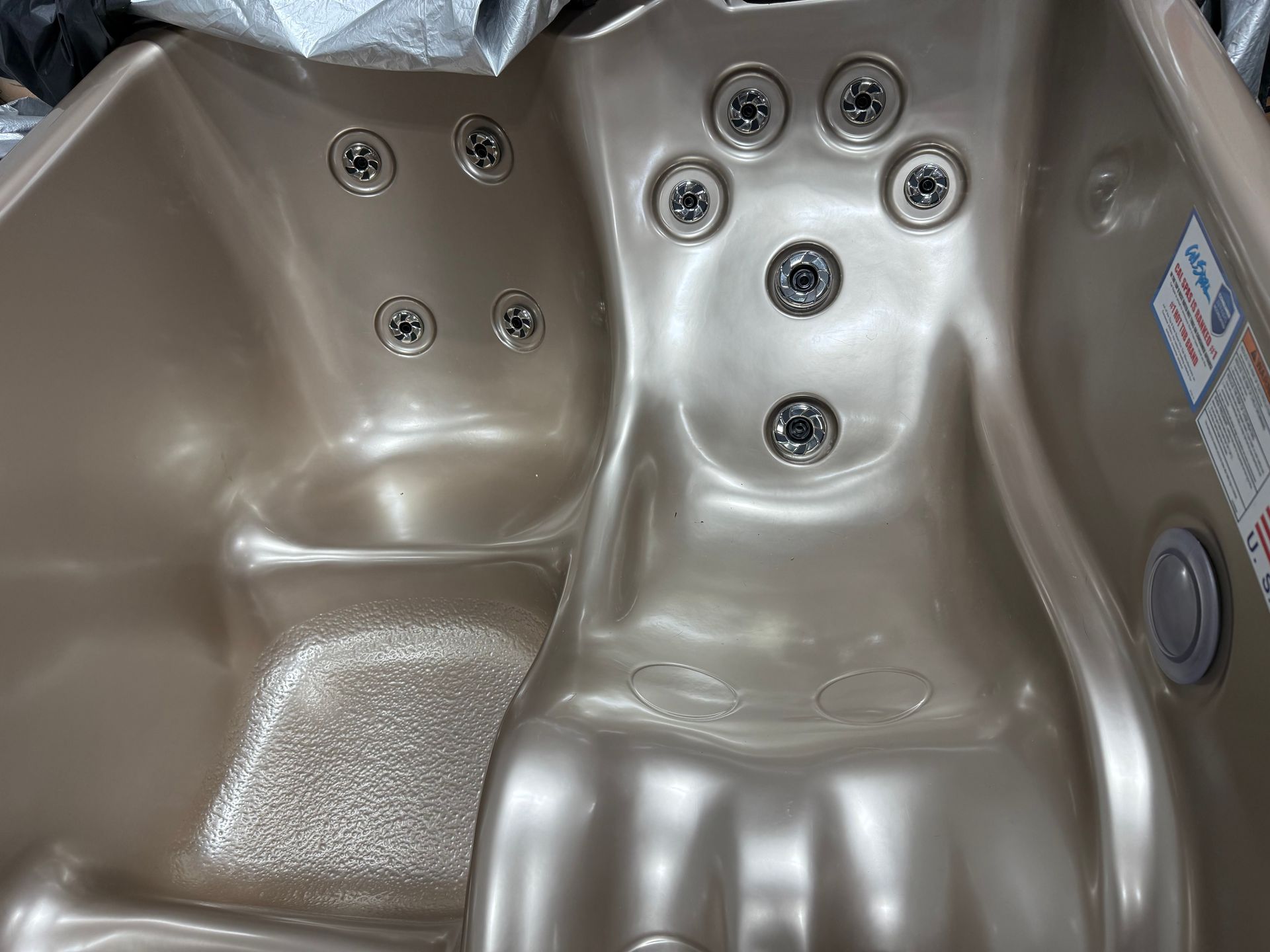 Tan hot tub interior with several water jets.