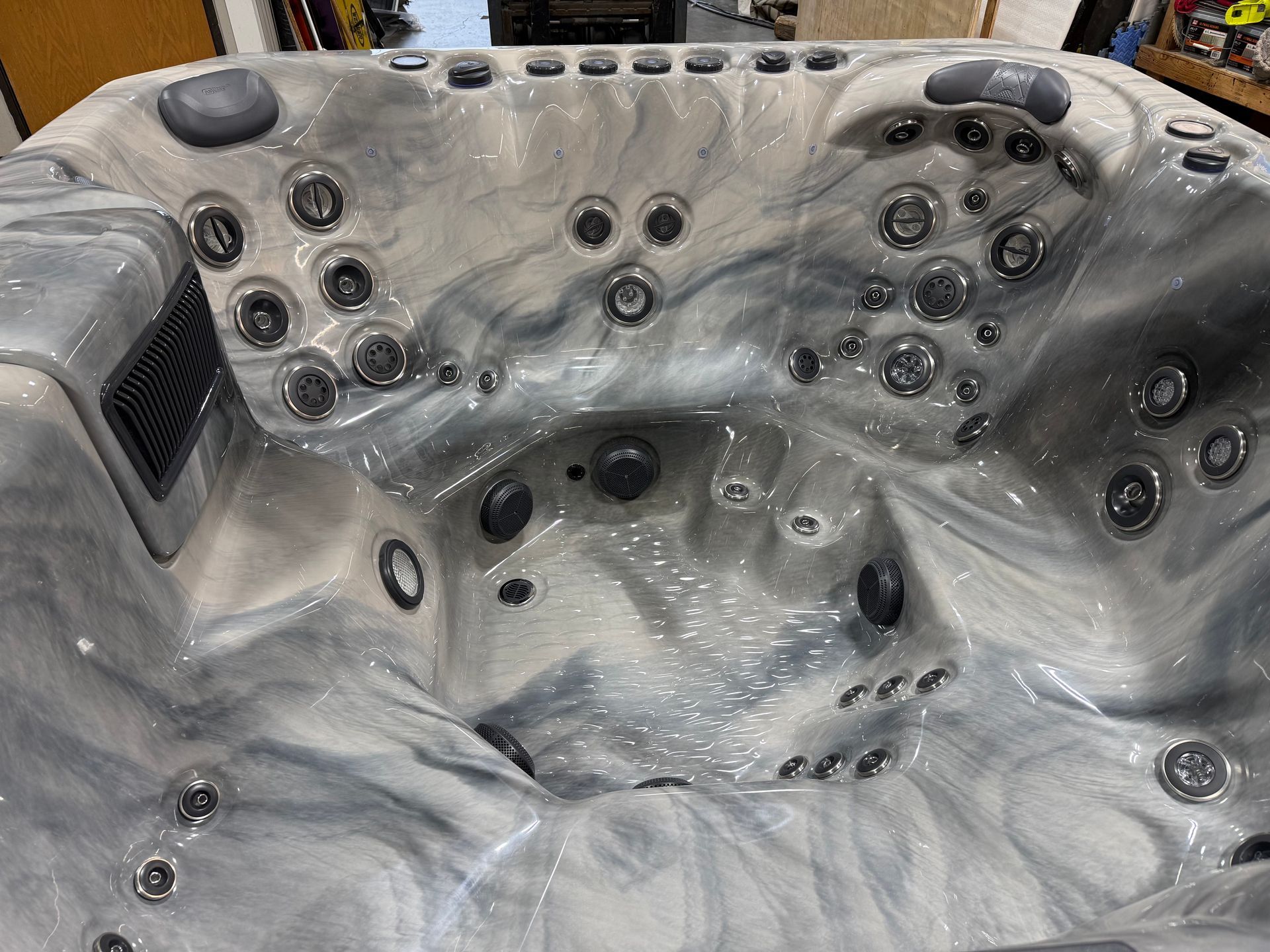 Close-up of a marbled, gray and white hot tub interior, filled with jets and seating.