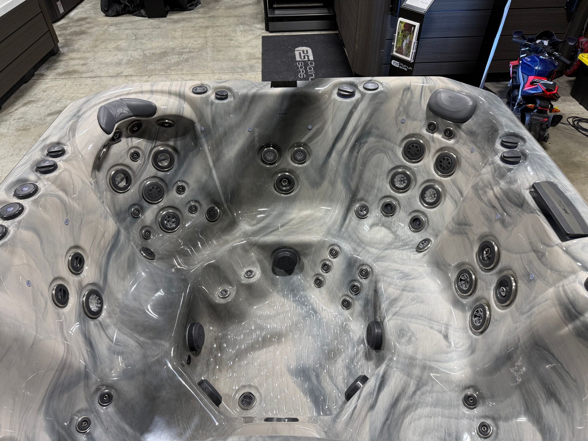 Hot tub interior with many black jets, swirled gray and white surface.