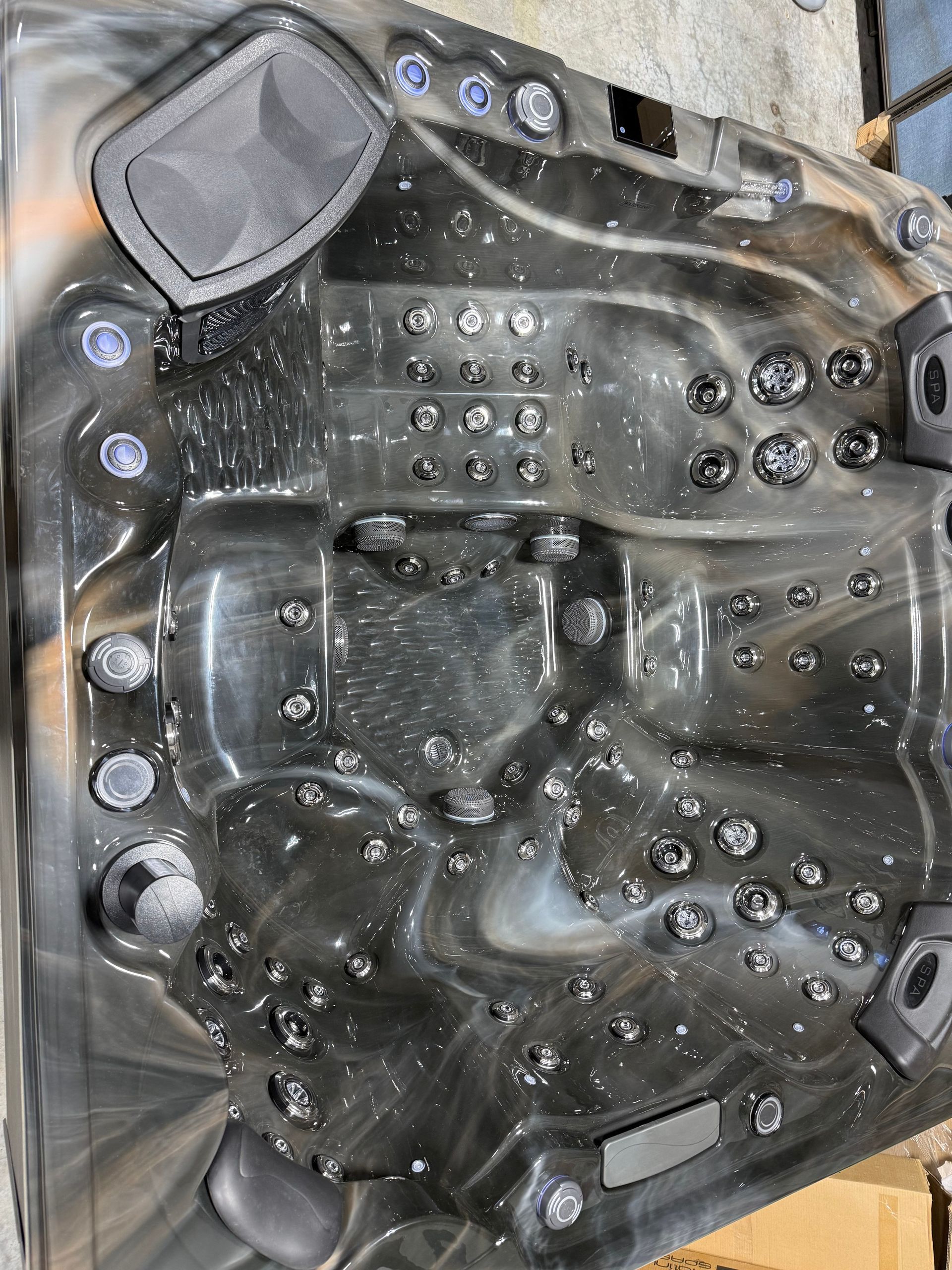 Dark hot tub interior with many jets and speakers; gray and black marbled pattern.