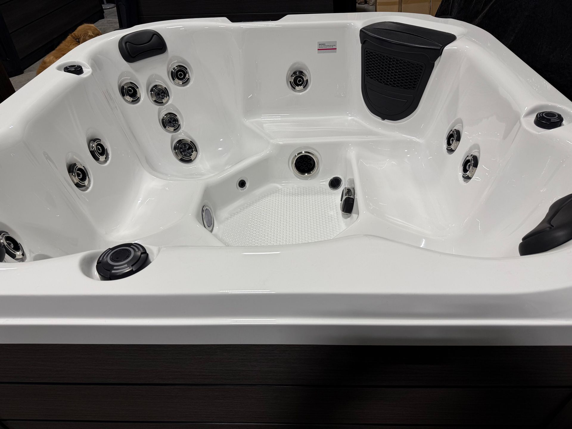 White hot tub with black jets, seating, and cover. Dark brown exterior.