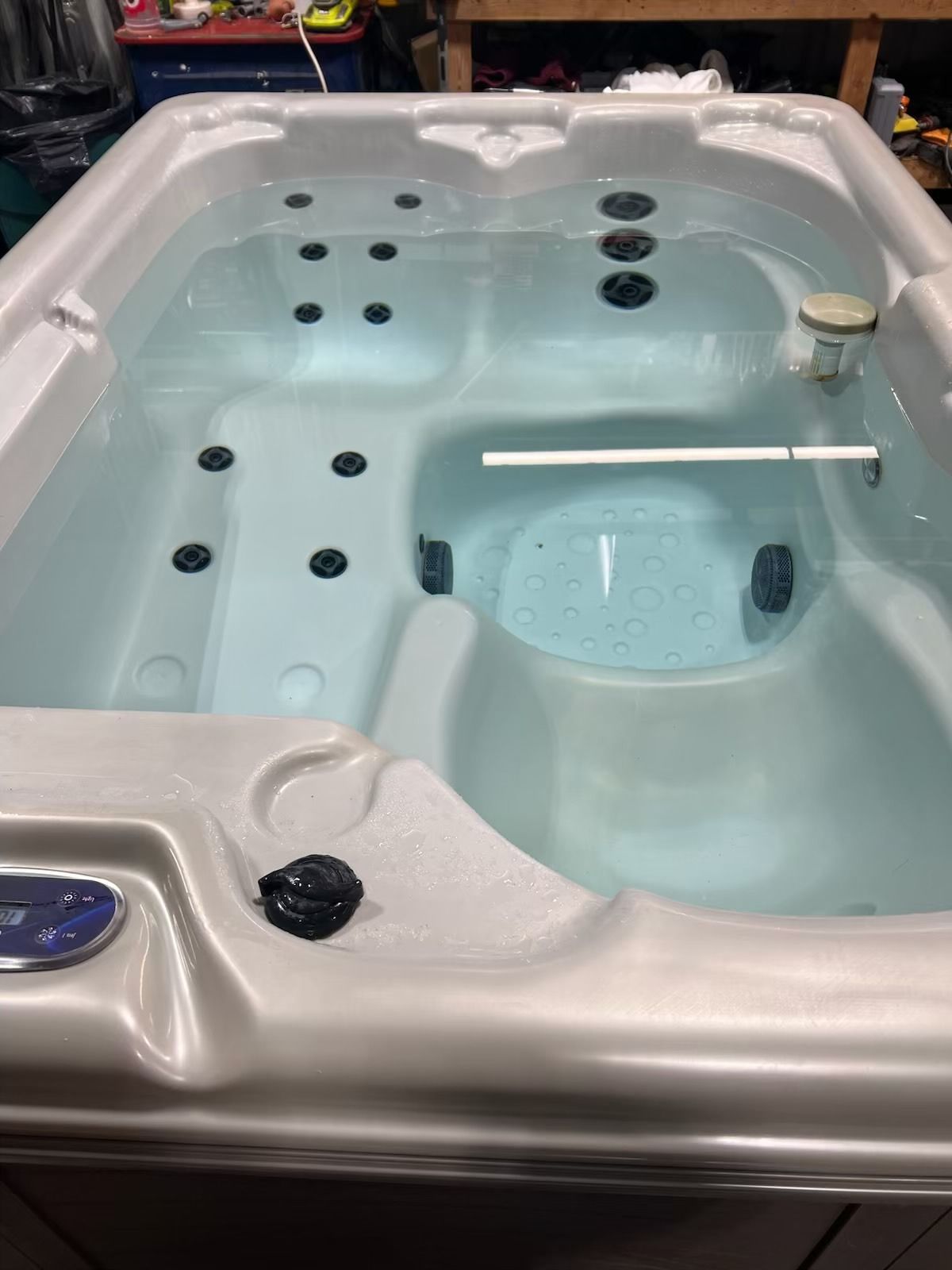 Hot tub filled with clear water, with several jets and a filtration system.