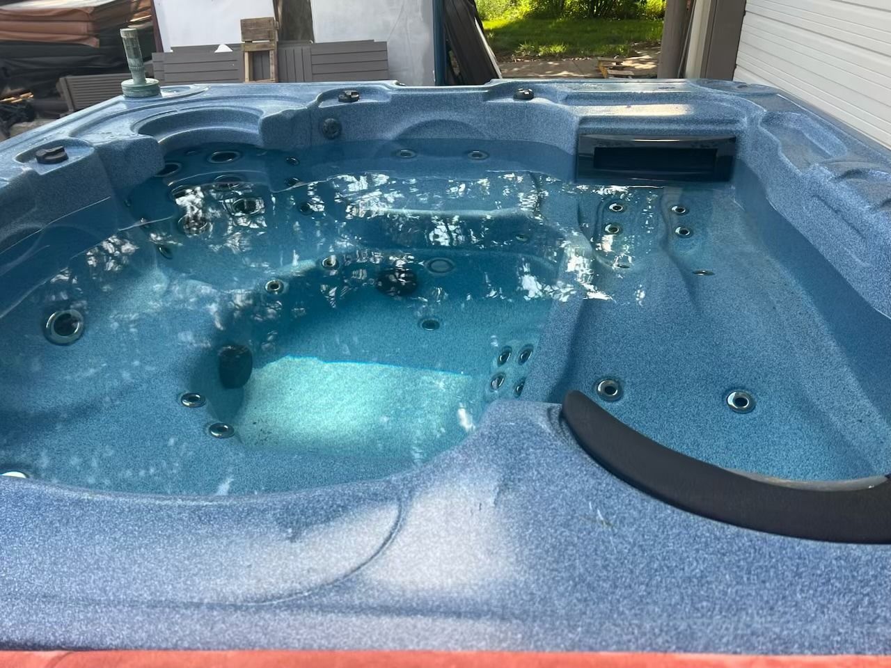 Blue hot tub filled with water, outdoors.