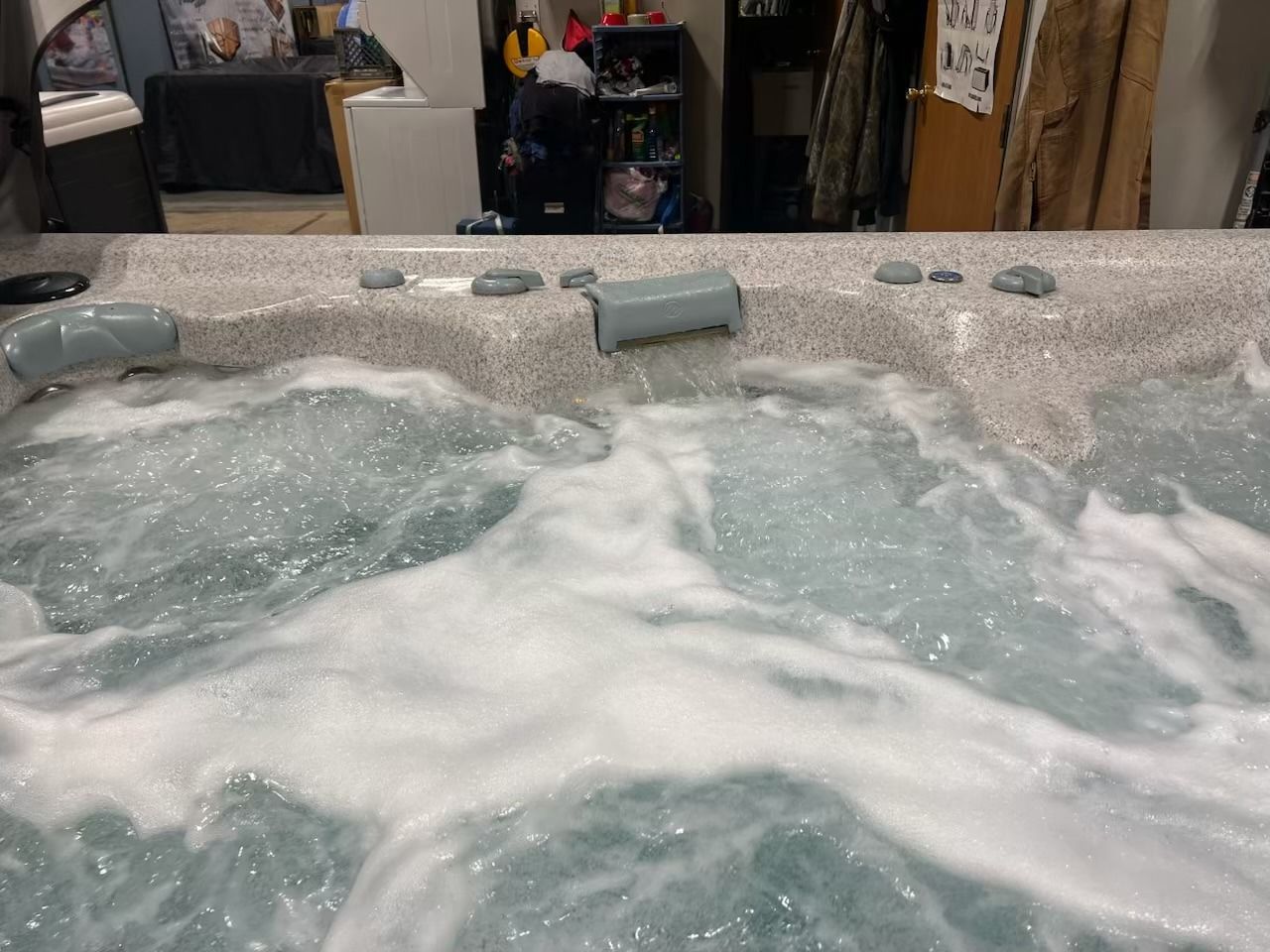 Hot tub with jets spraying water. Gray and beige spa edge, bubbles on the surface.