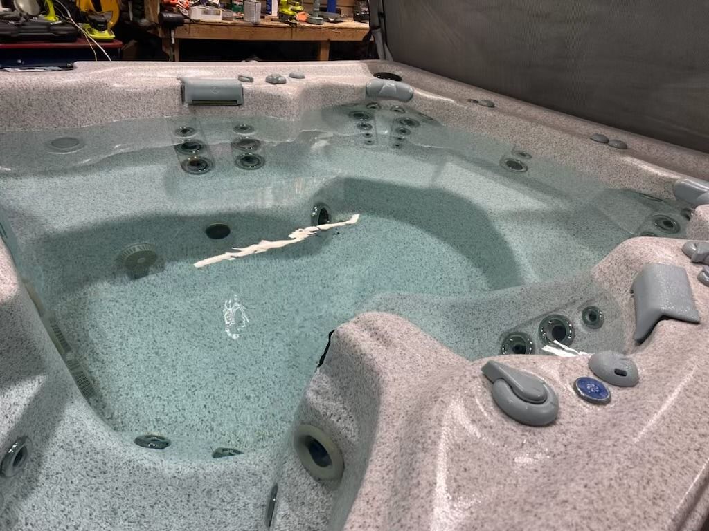 A partially filled, gray speckled hot tub with jets and water-level seating.
