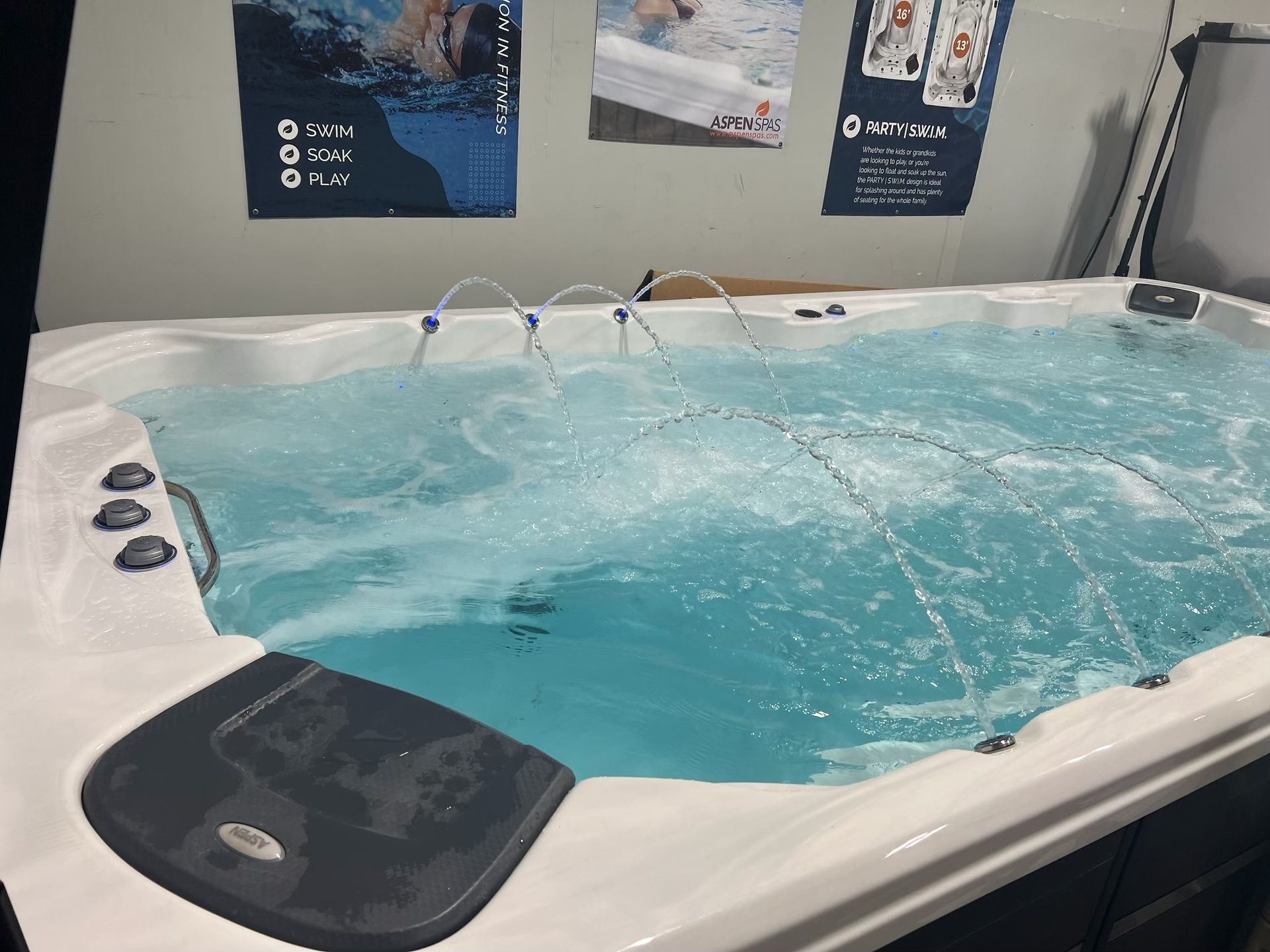 A rectangular, white swim spa filled with blue water. Water jets are active.