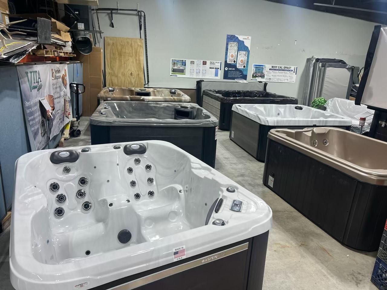 Several hot tubs on display in a showroom, various sizes and colors.