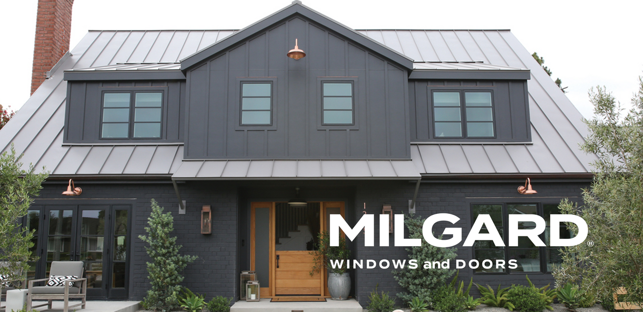 A black house with a metal roof and a sign that says milgard windows and doors