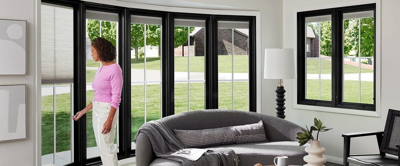 A woman is standing in a living room looking out of a window.