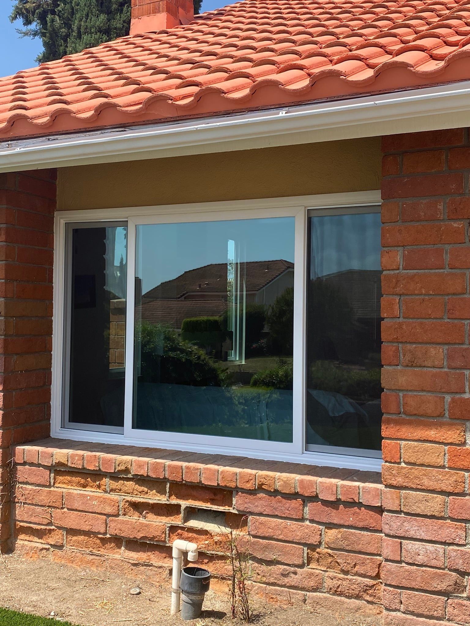 A brick house with a white window and a red tile roof.