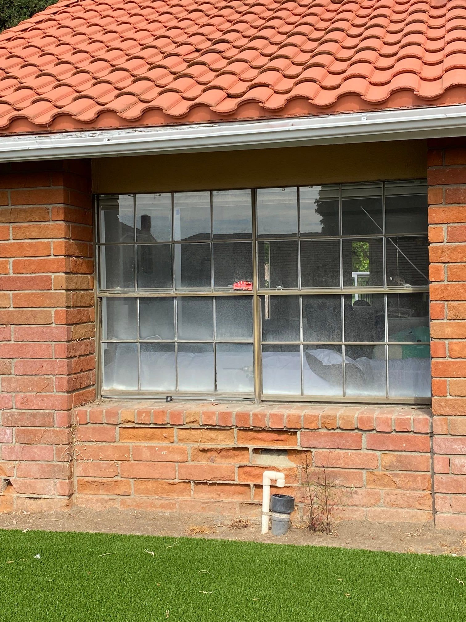 A brick house with a red tile roof and a window