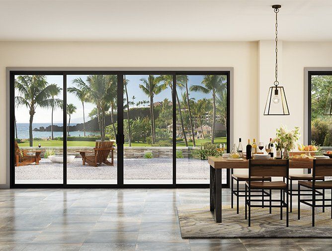 A dining room with a table and chairs and a view of the ocean.